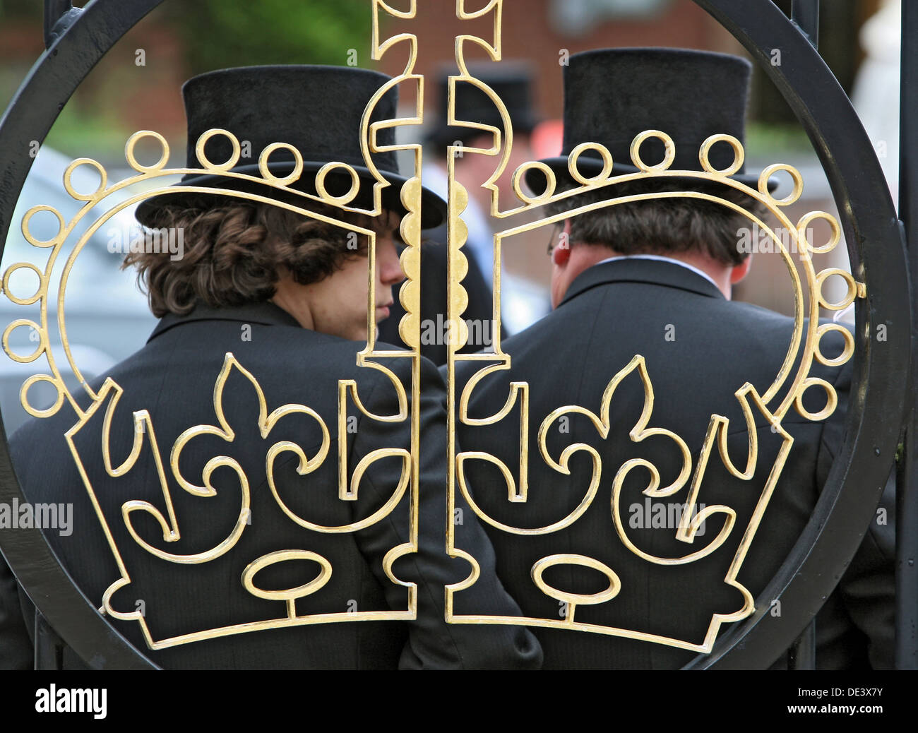 Ascot, United Kingdom, with cylindrical Men behind the image of a crown in an iron fence Stock Photo