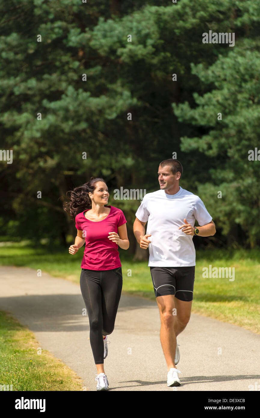 Smiling young couple running in park Stock Photo