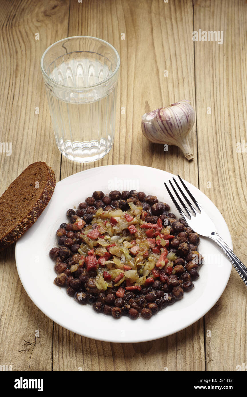 Gray peas with sausage, bacon and onion on wooden table Stock Photo