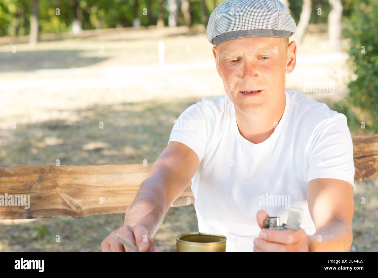 Middle-aged man about to light a cigarette concentrating on flicking his lighter to get a flame Stock Photo