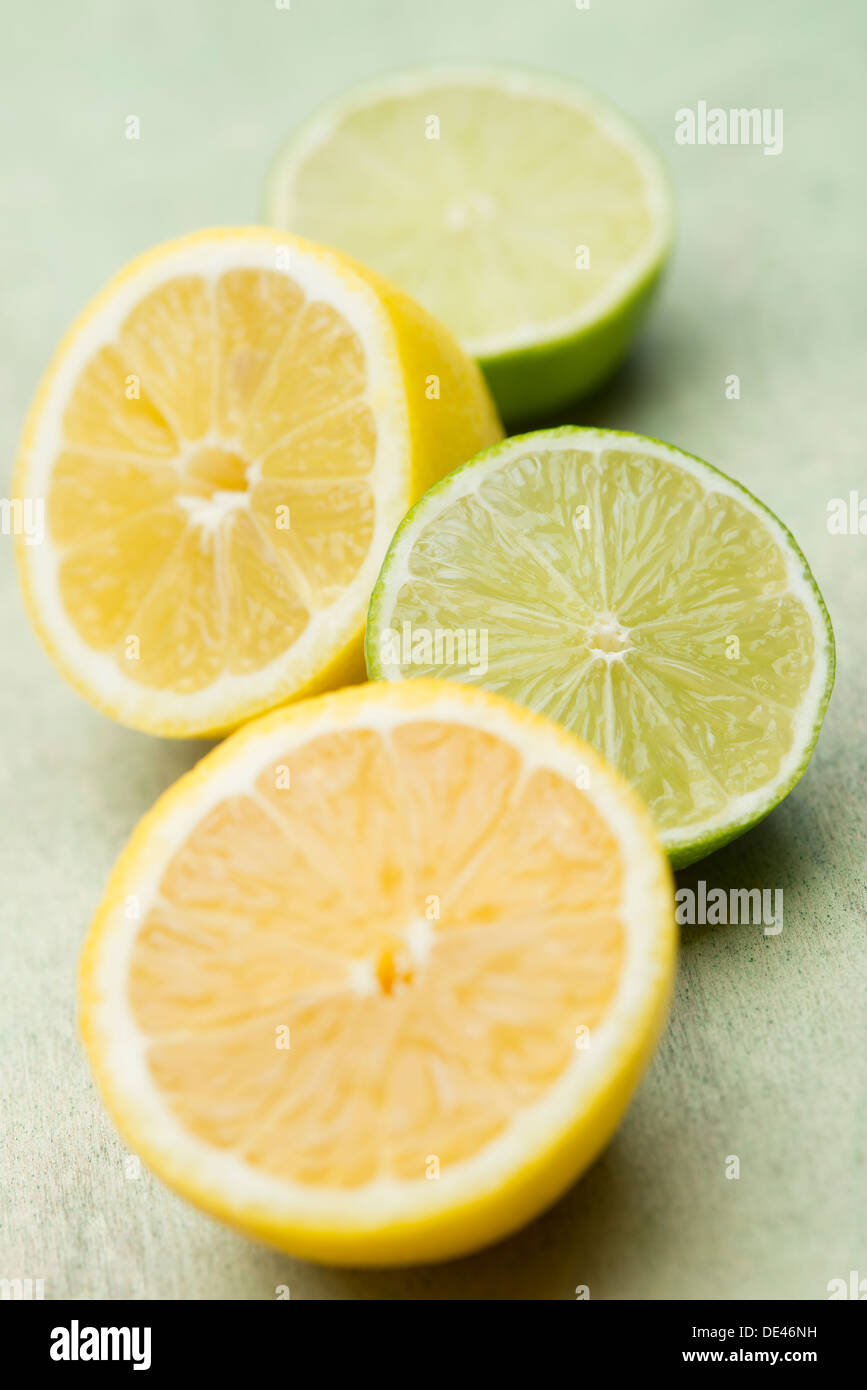 Delicious, fresh, juicy and appetizing lemons and limes cut in half and laid out on a wooden surface Stock Photo