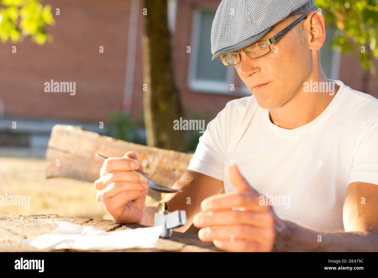 Caucasian middle-aged drug user preparing a dose of heroin for an intravenous injection Stock Photo