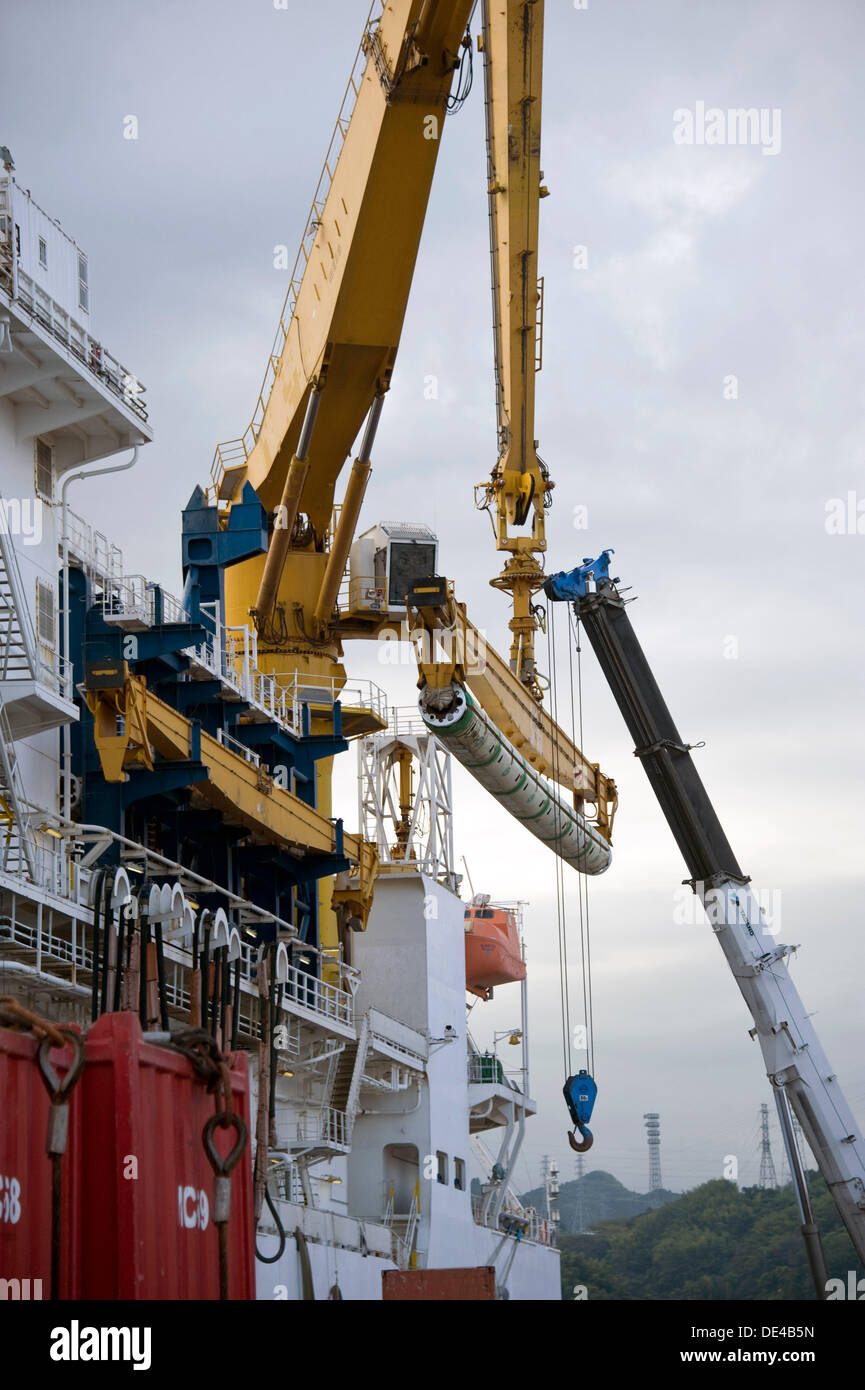 A crane lifts pipes used to lower the Riser drill used on the Chikyu ...