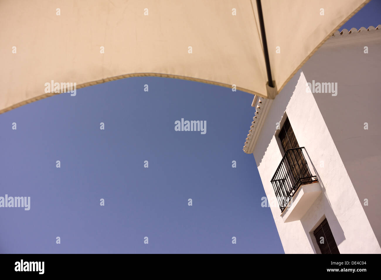 A Spanish Balcony framed by a street cafe parasol in the Andalusian town of Frigiliana. Stock Photo