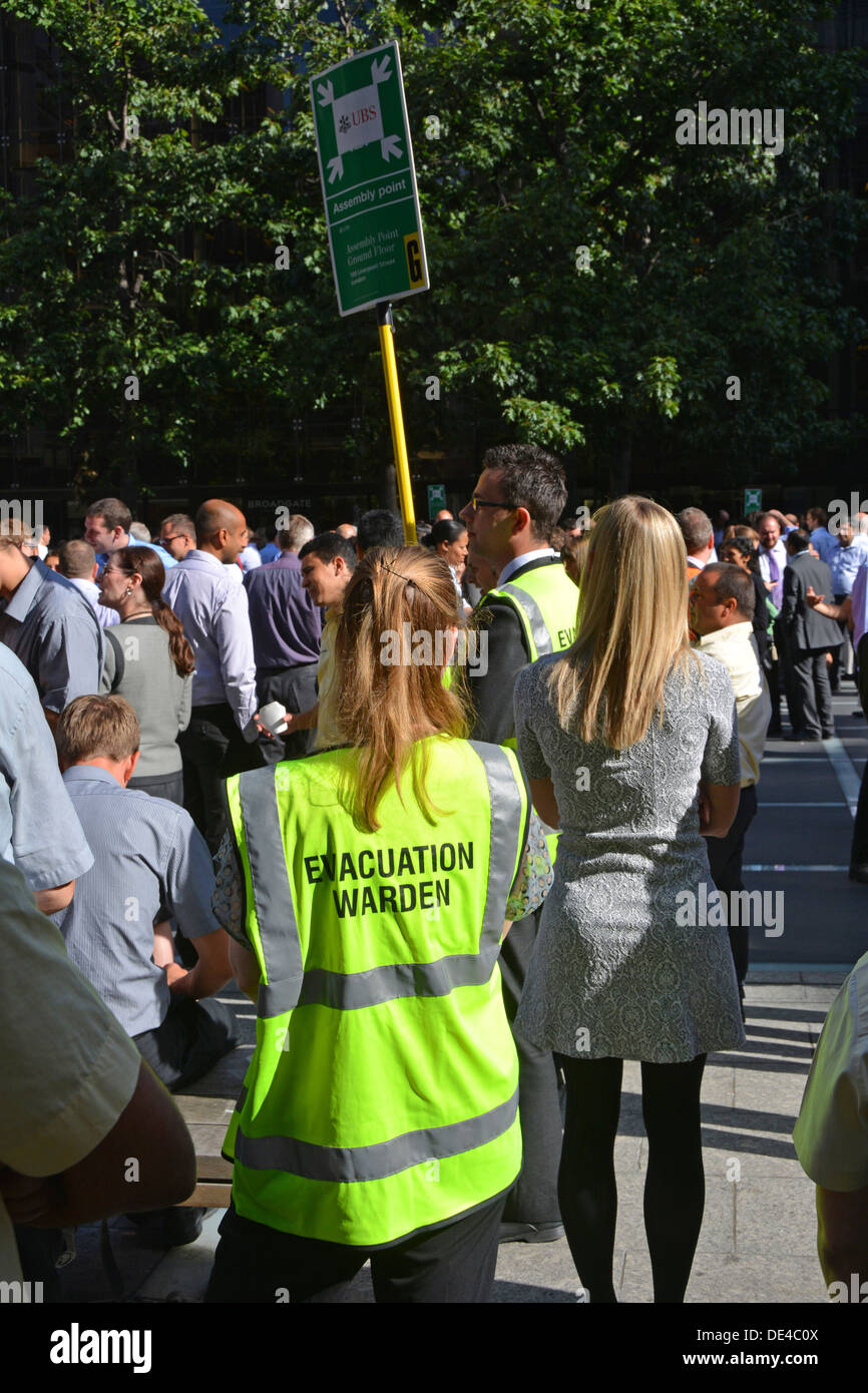 Practice office workers mass workforce evacuation of a large office complex under the supervision of staff wardens high vis jacket at muster point Stock Photo