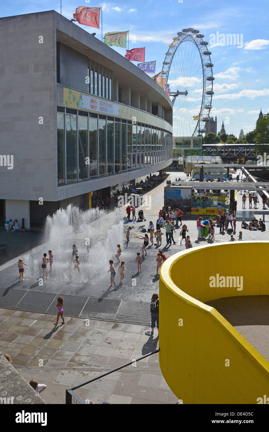 Summertime at Southbank complex kids playing in the Appearing Rooms water fountain outside the Royal Festival Hall with London Eye beyond England UK Stock Photo