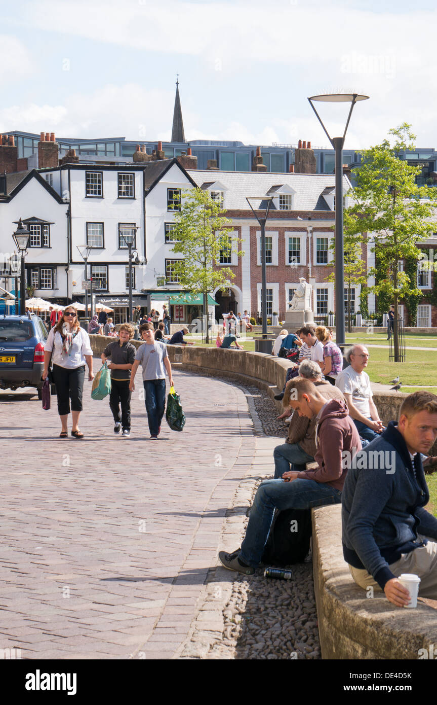 People sitting on a wall enjoying summer sunshine, Cathedral Green, Exeter, Devon, England, UK Stock Photo