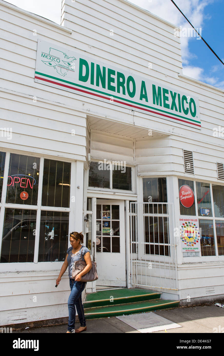 WOODBURN, OREGON, USA - Woman exits store with Dinero a Mexico sign that offers remittance service to Mexican immigrants. Stock Photo