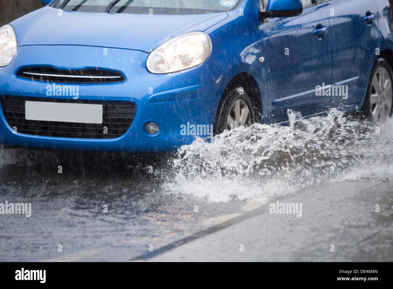 Blue car driving through flooded road Stock Photo - Alamy