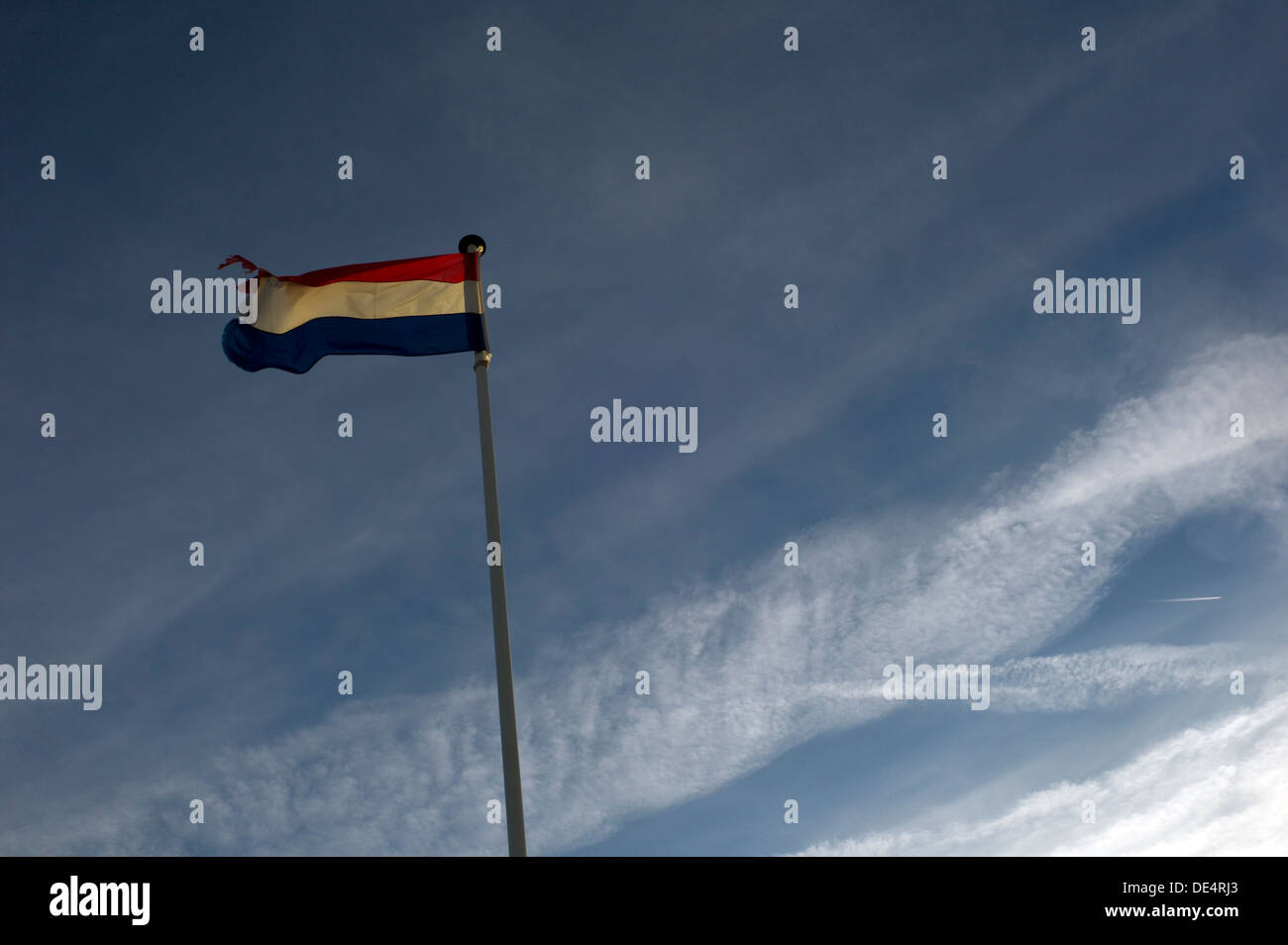 Tattered flag Netherlands, blue sky, clouds Stock Photo