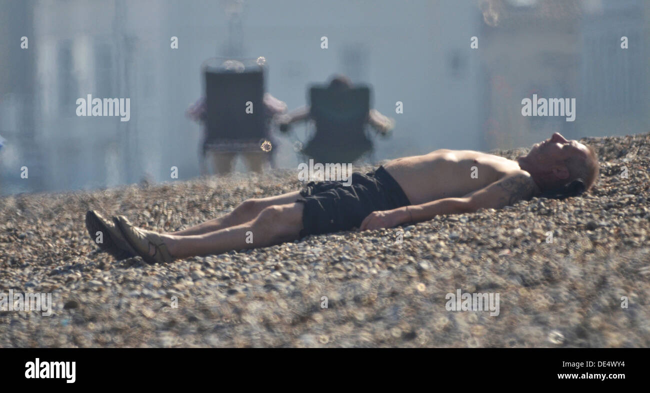 man asleep on shingle beach Stock Photo