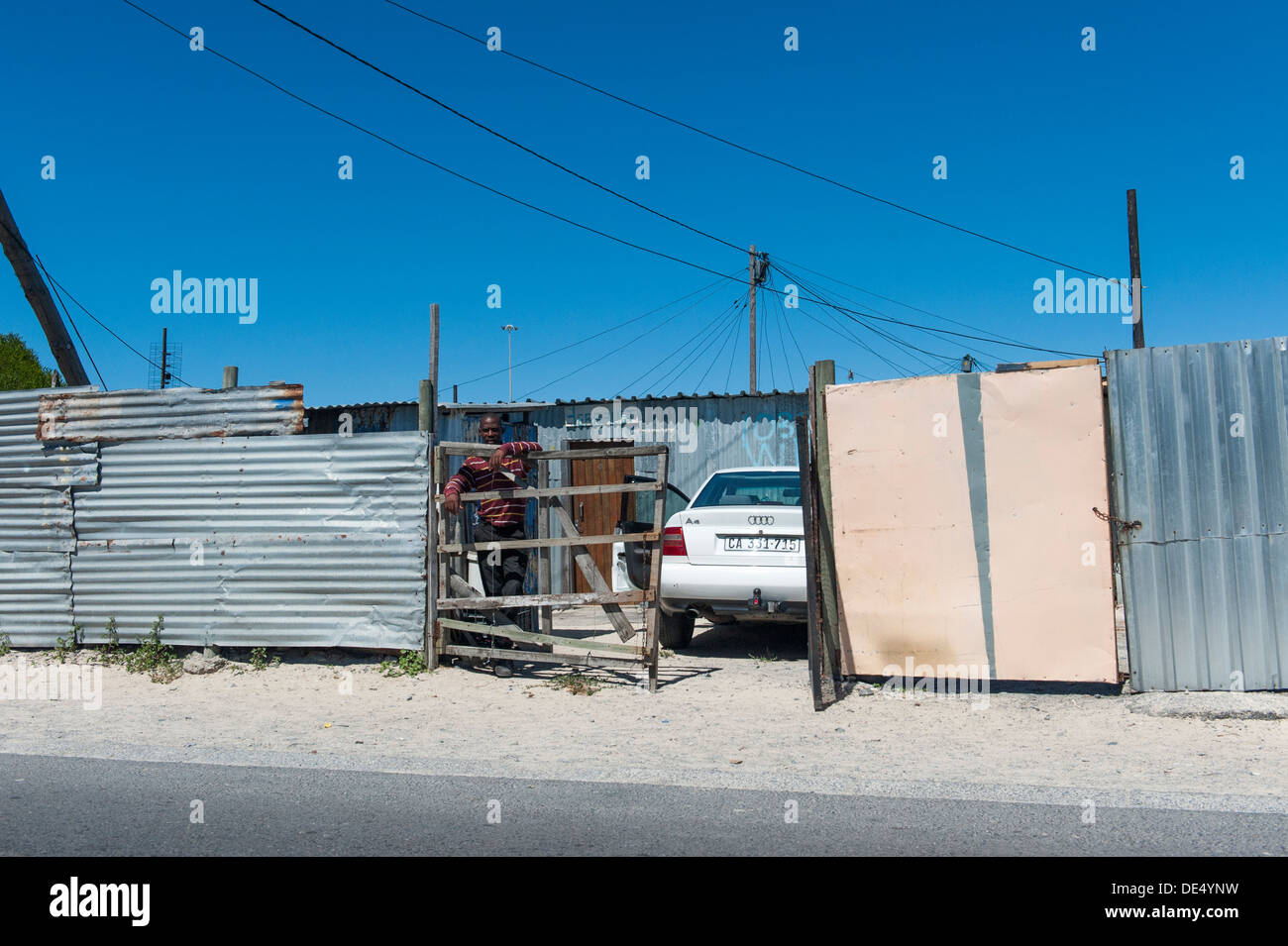Car owner and parked car in front of a tin shack in Khayelitsha, Cape Town, South Africa Stock Photo