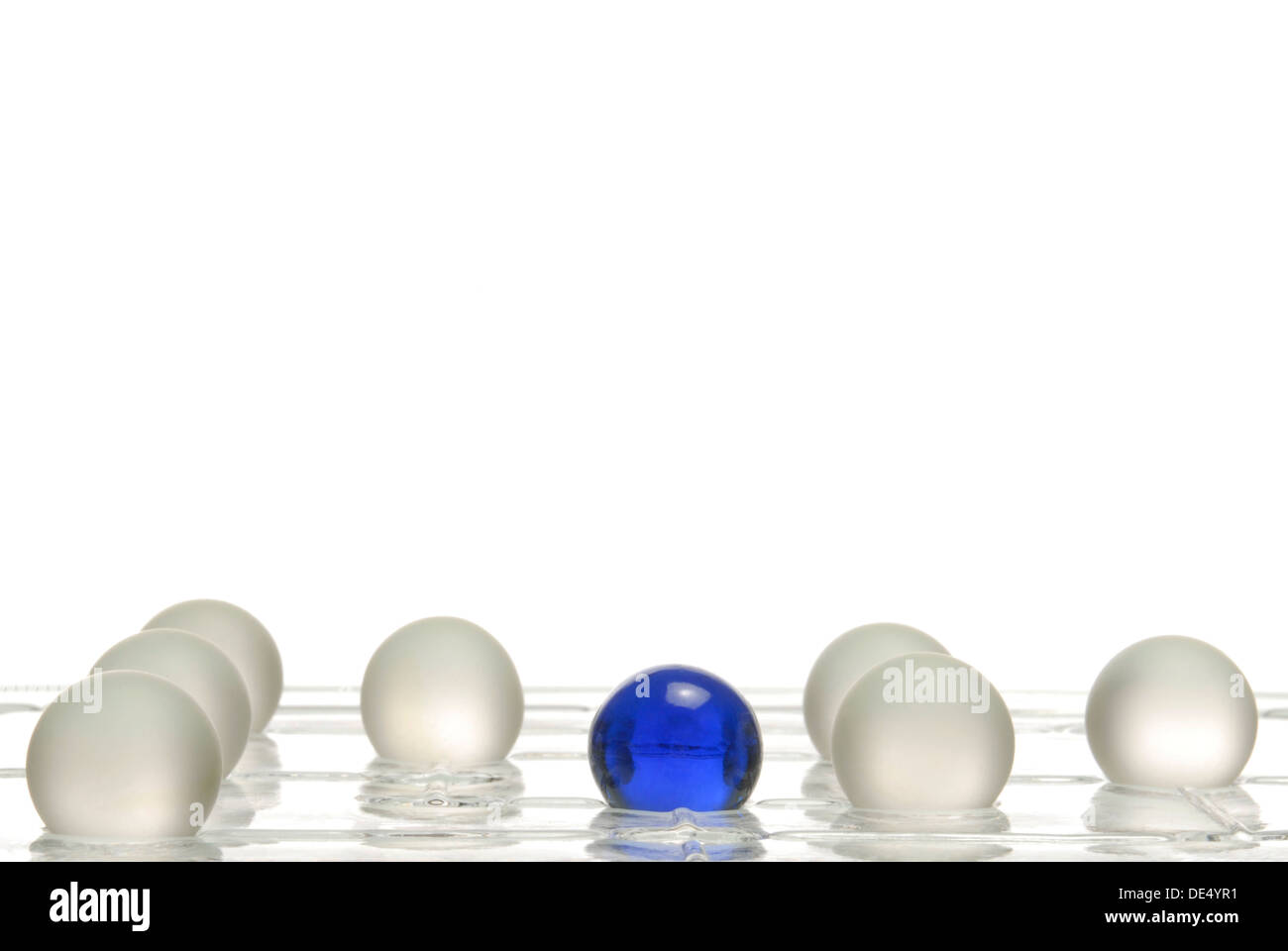 White balls and one blue ball on a game board, symbolic image for being different Stock Photo