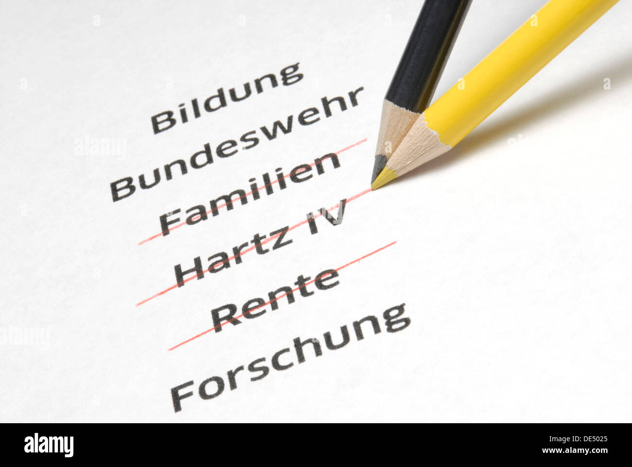 A yellow and a black pencil crossing out the letterings 'Familien', 'Hartz IV' and 'Rente', German for 'families', 'Hartz IV', a Stock Photo