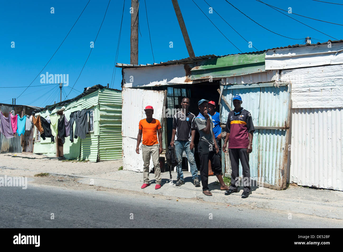 People standing in front of a tin shack in Khayelitsha, a partially informal township in Cape Town, Western Cape, South Africa Stock Photo
