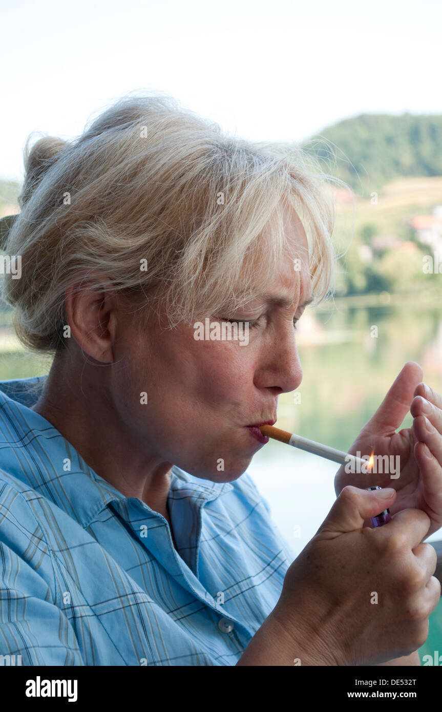 Middle aged woman lighting up a cigarette Stock Photo