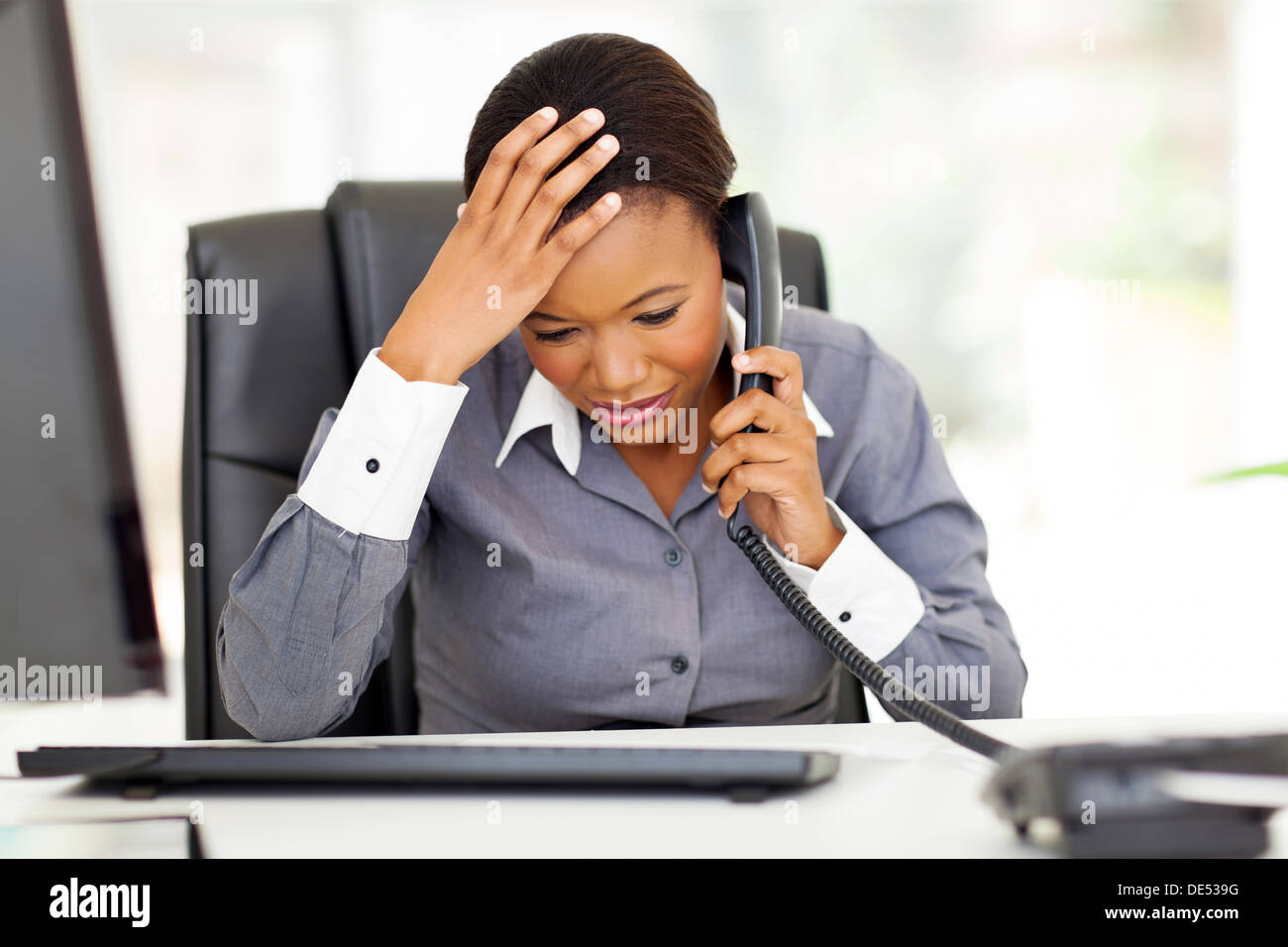 confused African office worker talking on telephone in office Stock Photo