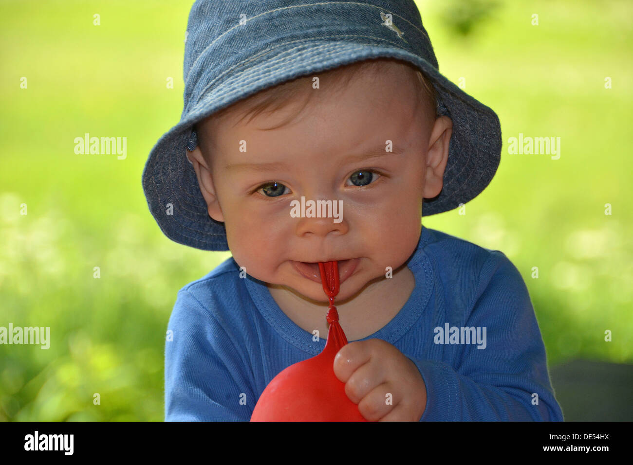 Boy, 10 months, playing with a red balloon outdoors Stock Photo