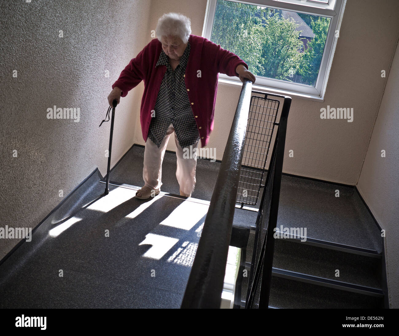 Independent elderly senior pensioner lady at 99 years climbing two flights of stairs aided only by her walking stick Stock Photo