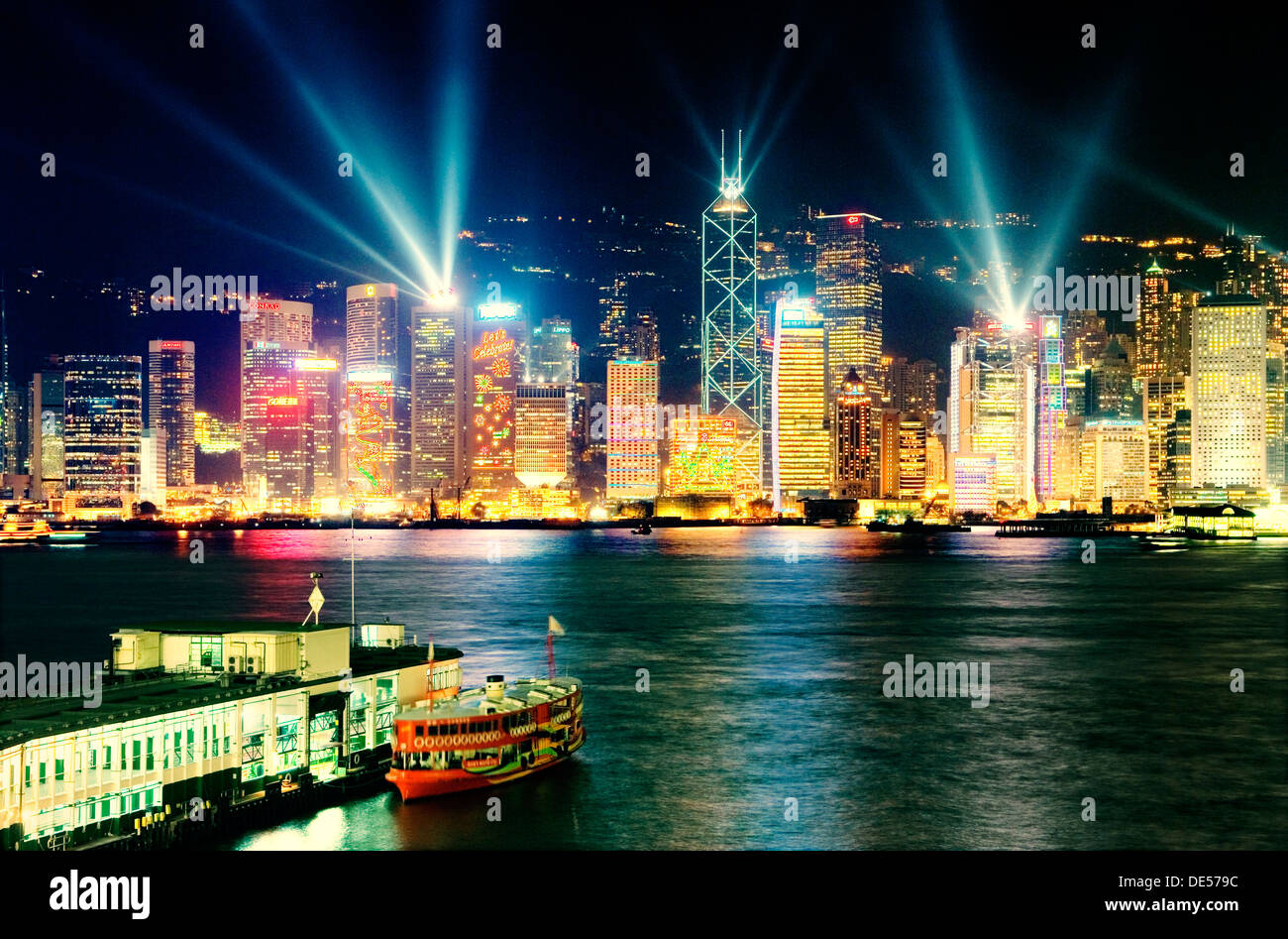 Hong Kong Island China city skyline with night laser light show seen across Victoria Harbour from Kowloon Star Ferry terminal Stock Photo