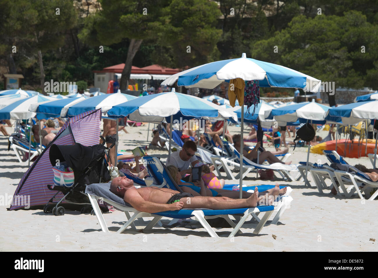 Tourists chill or sunbath in the beach in the Spanish Balearic islands