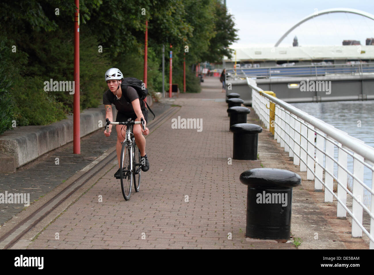 A young woman cycles along the River Clyde walkway in Glasgow, Scotland, UK. Stock Photo