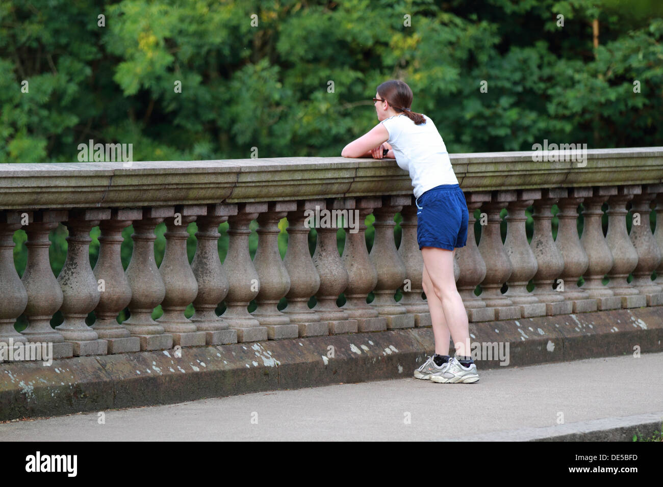 A young woman rests on a bridge after a long run Stock Photo
