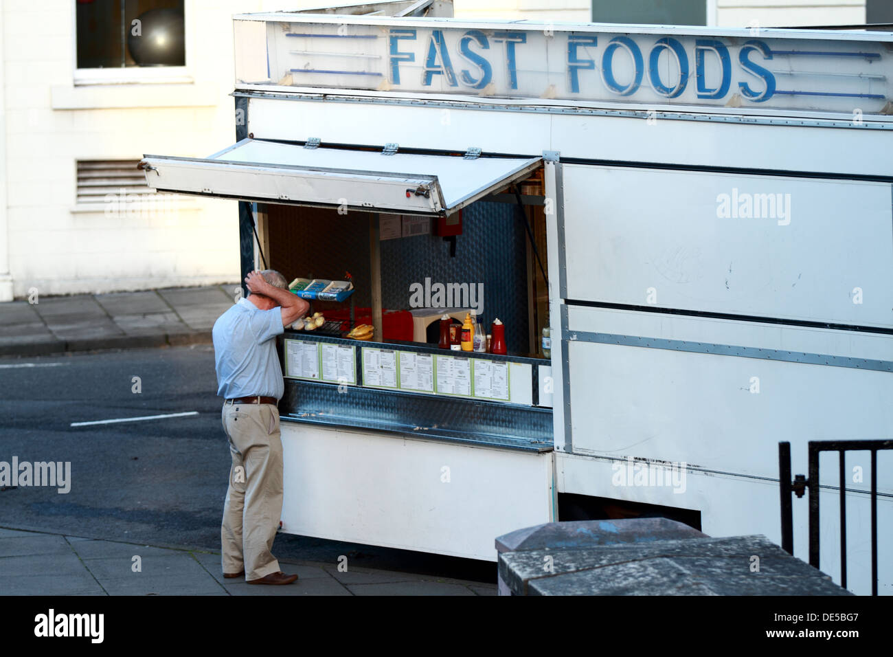 An elderly man seems confused when ordering from a fast food burger van. Stock Photo