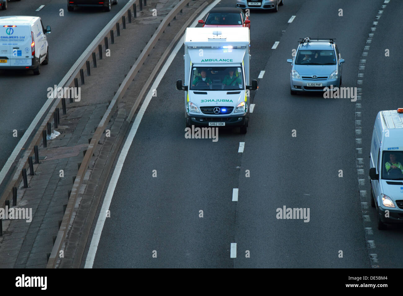 A Scottish Ambulance Service vehicle rushes down the M8 motorway with sirens and blue lights to an accident. Stock Photo