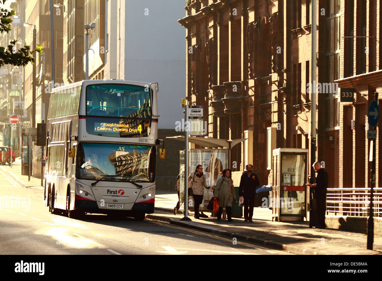Number 4 First Bus Glasgow drops off passengers in Glasgow City Centre, in the morning sunlight Stock Photo