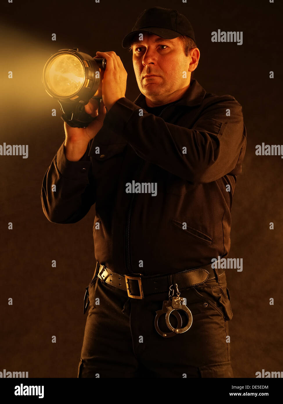 Policeman with lit torch searching the area Stock Photo