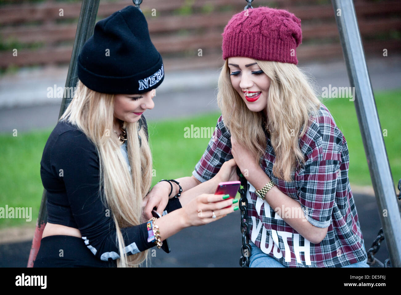 Two teenage girls outside looking at their mobile phone. Stock Photo