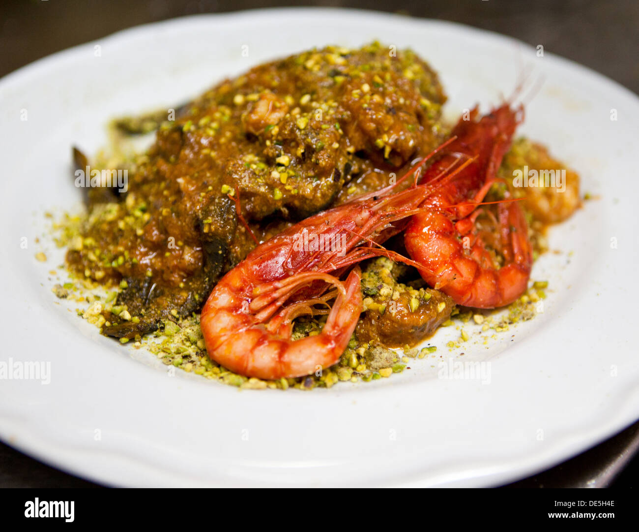 A Black pasta with King Prawn, tomato with Pistachio sauce dish served