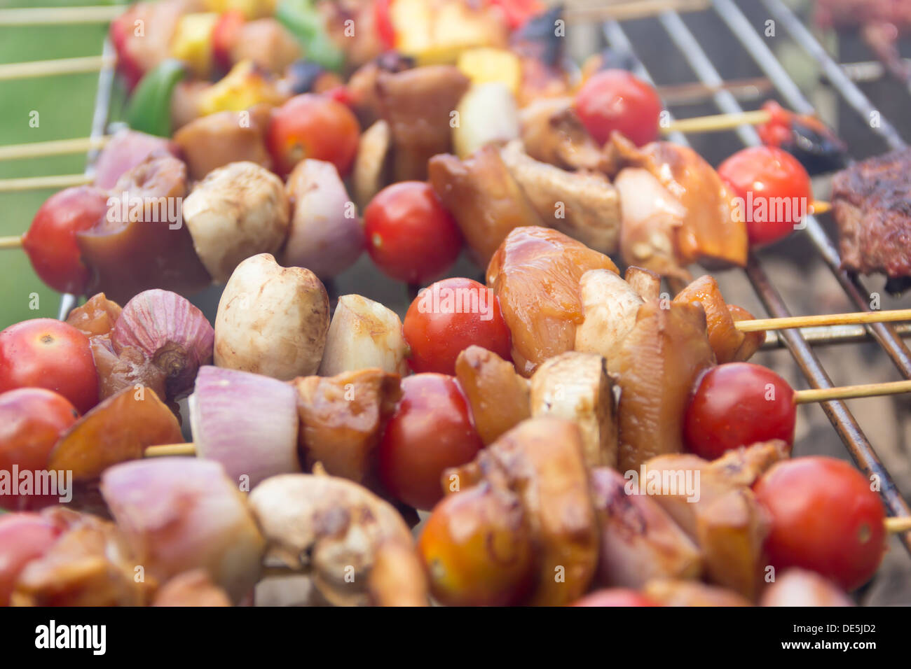 Chicken kebab skewers cooking on a large open charcoal barbecue catering for a party Stock Photo