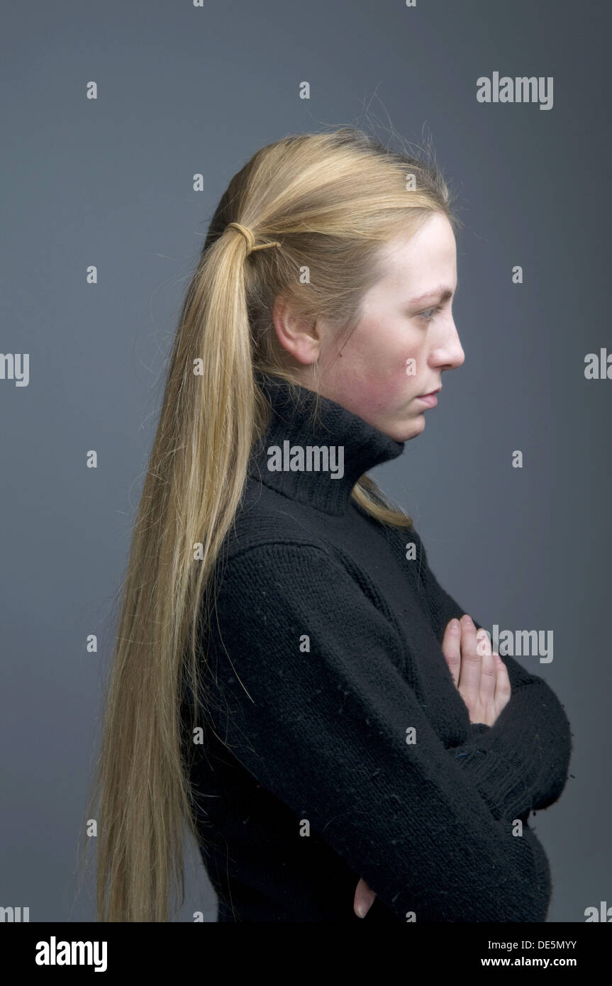 side on profile view of teenage girl with her hair in pigtails looking moody, stroppy, introverted Stock Photo