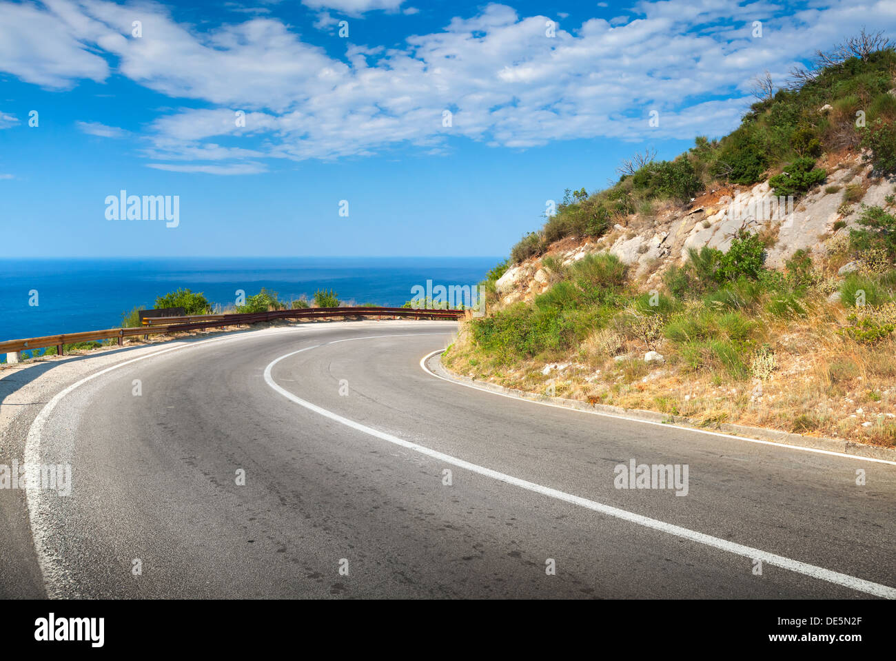 Turn of mountain asphalt road with blue sky and sea on a background Stock Photo