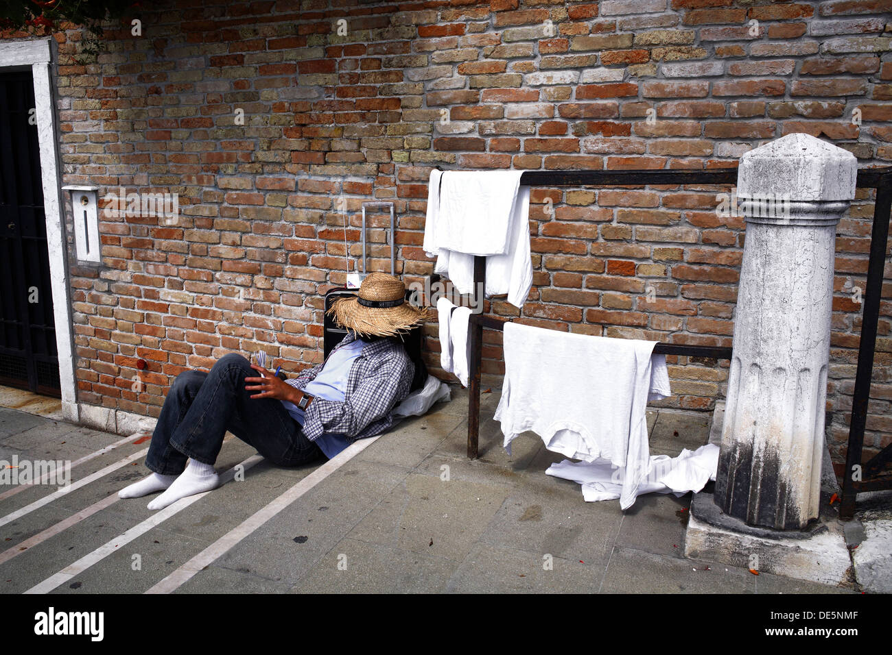 Traveling Man Resting on Steps While His Washing Dries, Venice Italy Stock Photo