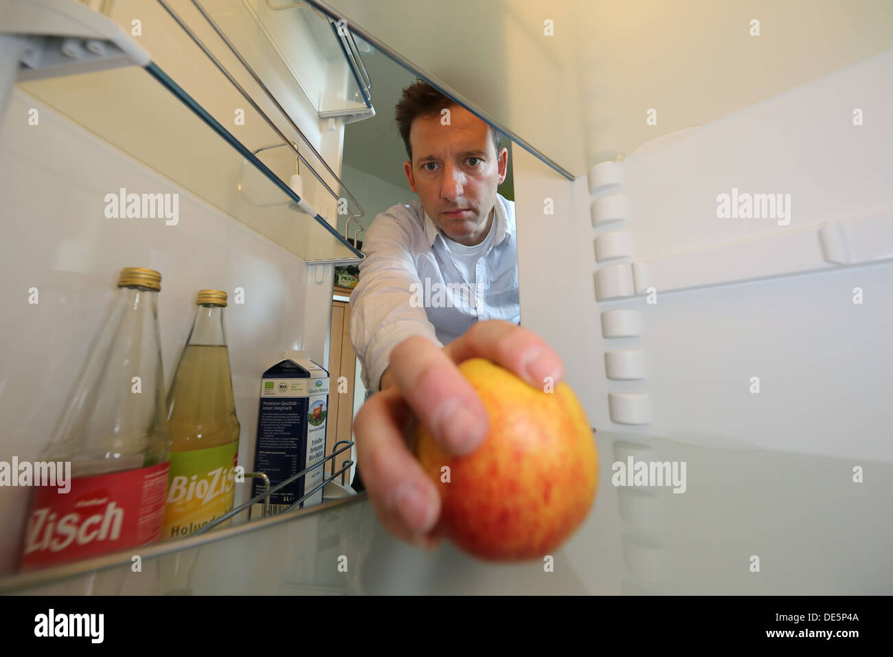 Berlin, Germany, Claus brings an apple from his nearly empty fridge Stock Photo