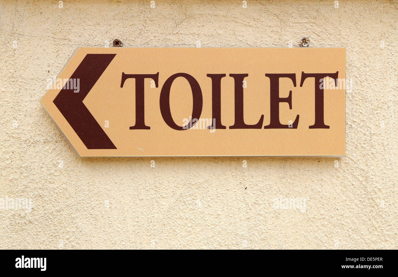 toilet sign with arrow on the wall Stock Photo