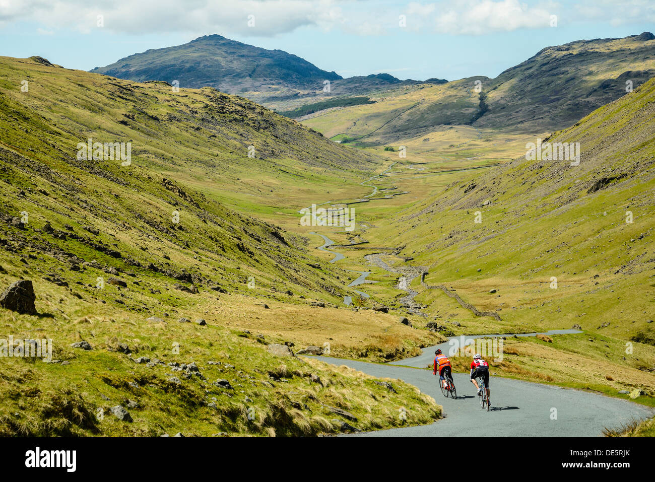 Cyclists descend the steep west side of Wrynose Pass in the English Lake District with Harter Fell behind Stock Photo