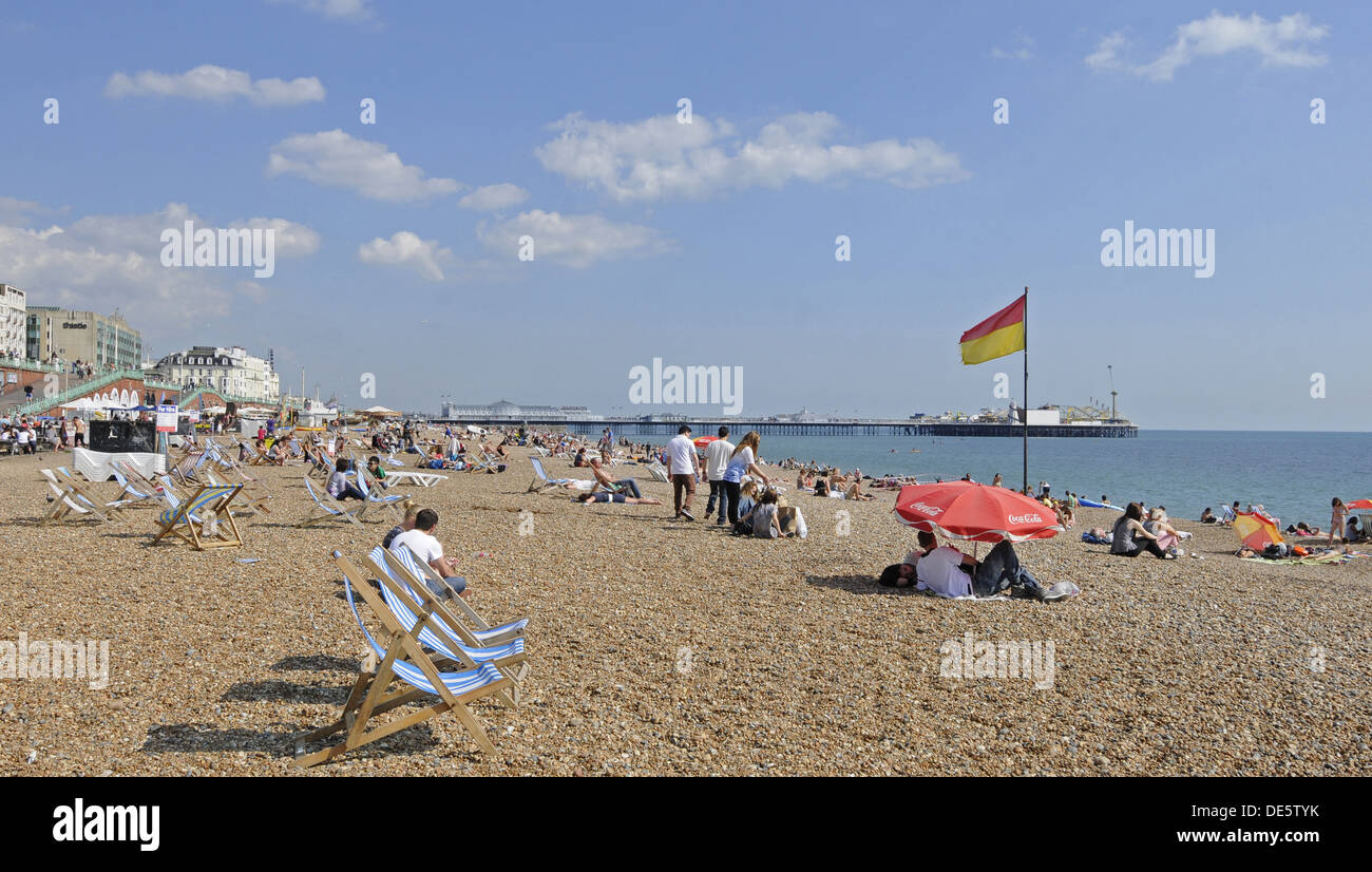 People sunbathing on beach with Pier Brighton East Sussex England Stock Photo