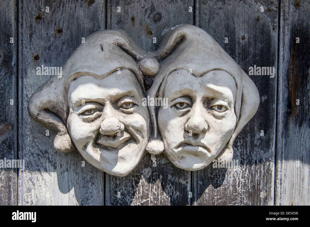 Commedia dell’arte sculpture faces made of pottery on a wooden door, UK Stock Photo