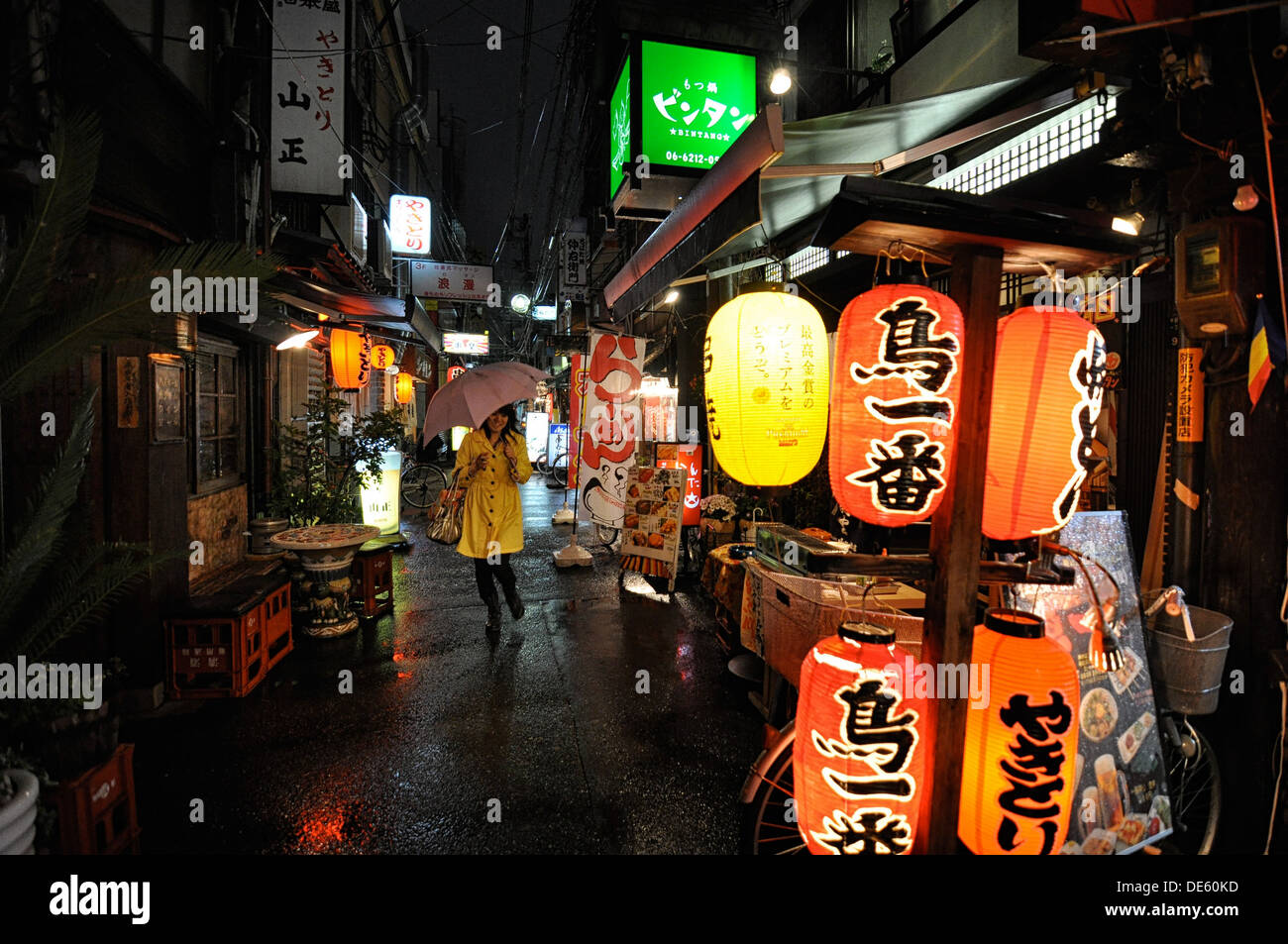 A woman running through rain in the entertainment district of Namba in Osaka, Japan. Stock Photo