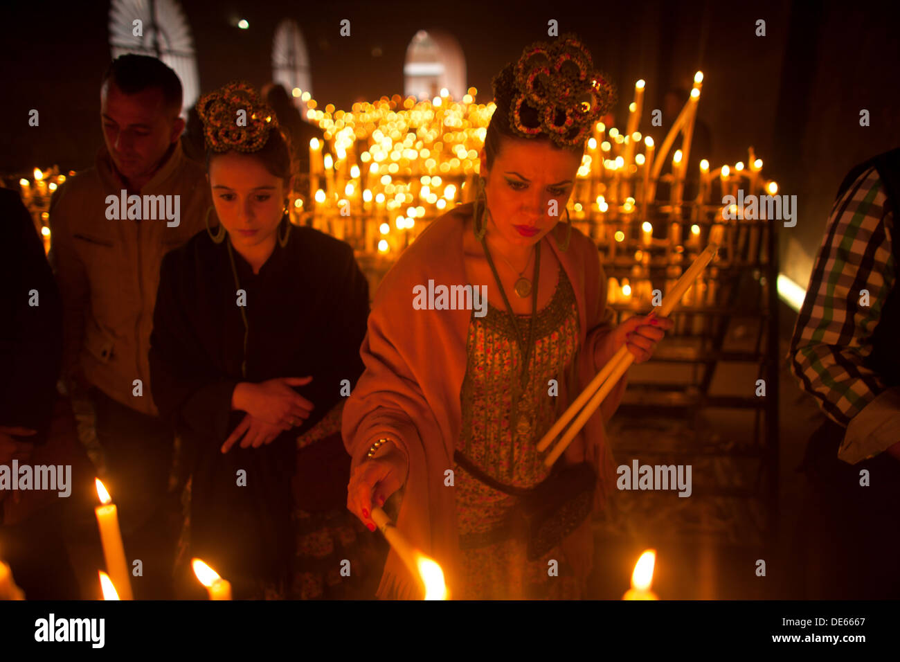 A woman lights a candle in the Votive Room of the shrine of the Virgin of Rocio, in Almonte, Donana National Park Stock Photo