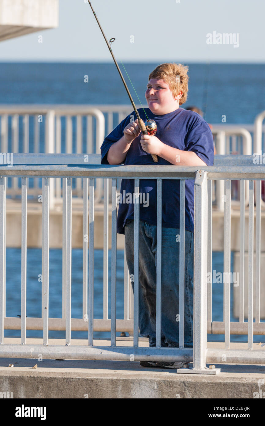 Overweight youth fishing from the fishing pier in the Gulf of Mexico at Cedar Key, Florida Stock Photo