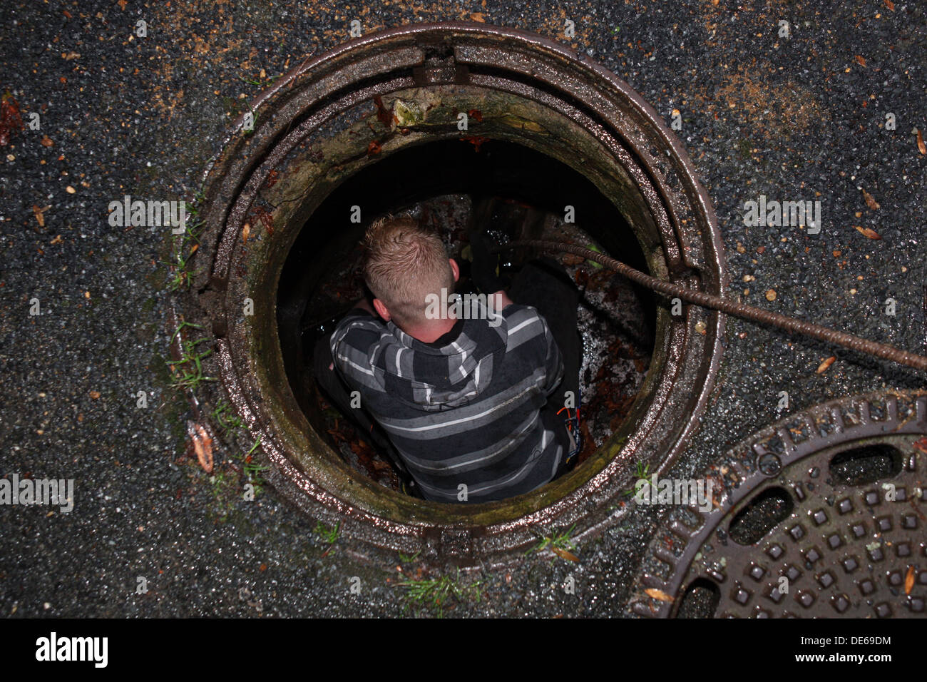 Berlin, Germany, man working without protective clothing in a manhole Stock Photo