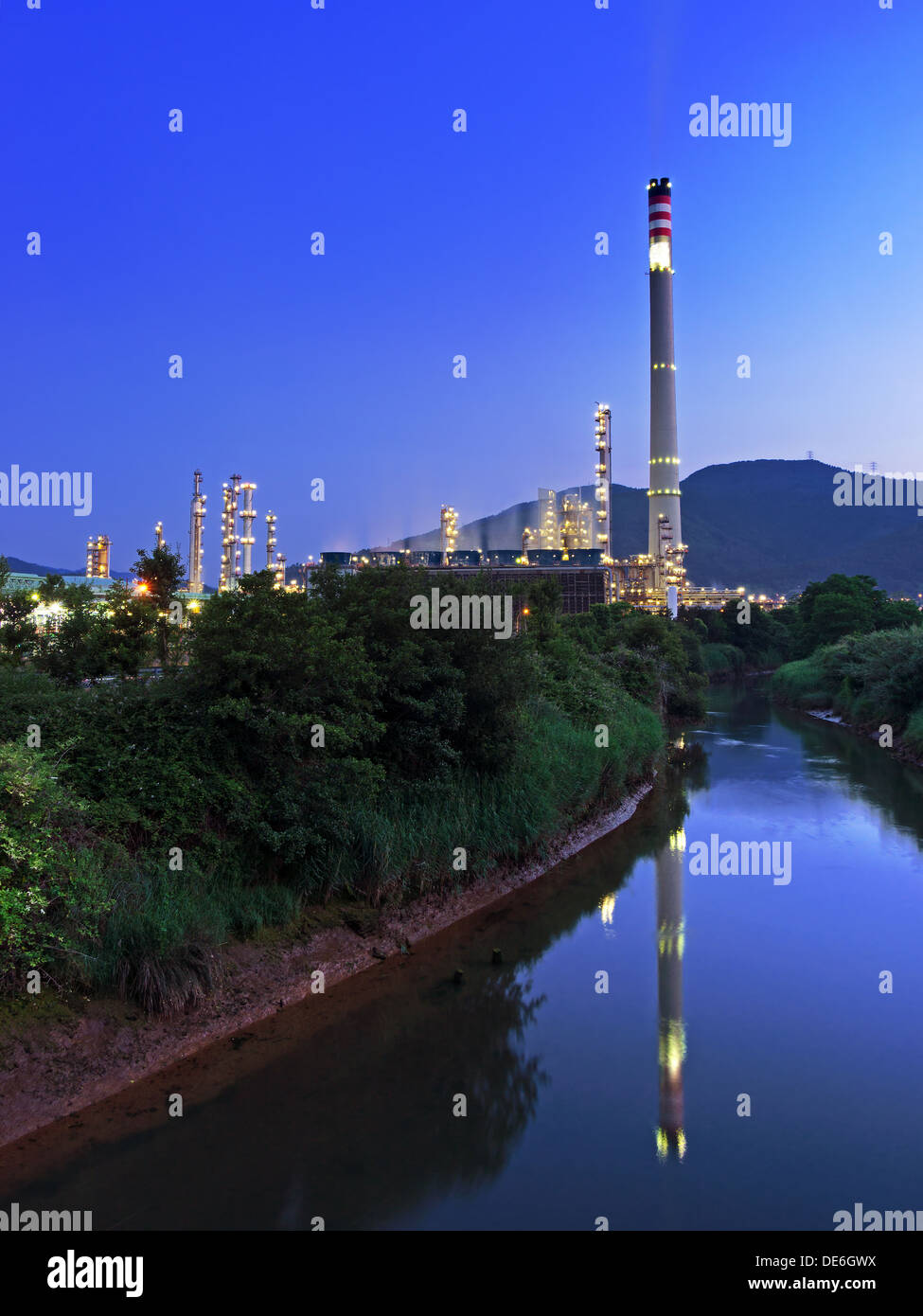 industrial refinery with smokestack near a river Stock Photo