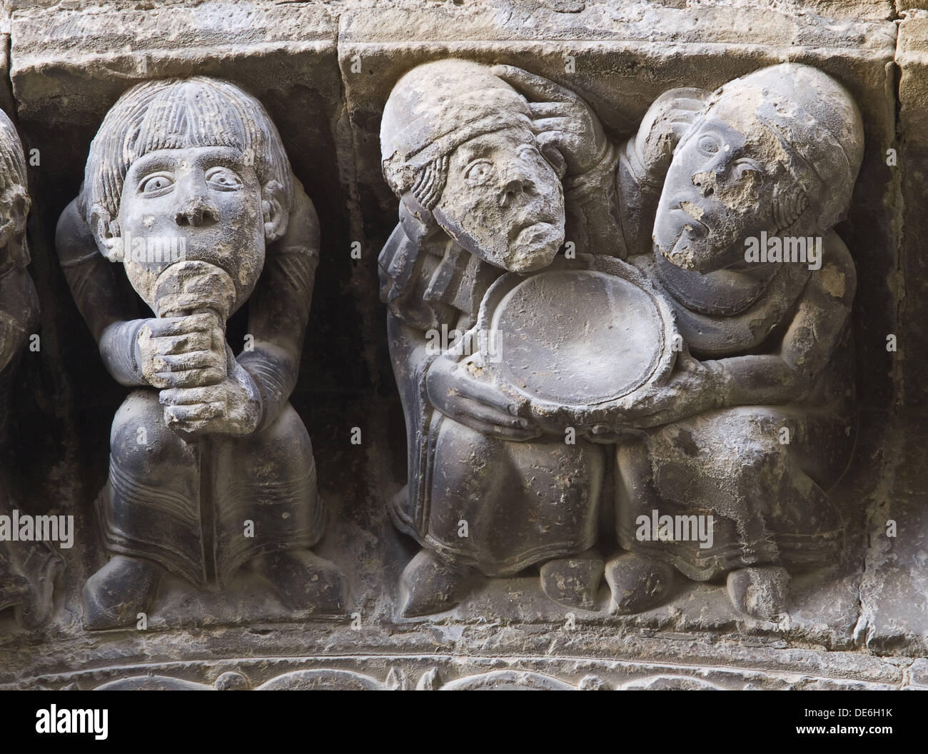 Voussoirs carved with depictions of a musician playing flute and two men holding an empty plate, Romanesque church of Santa Stock Photo