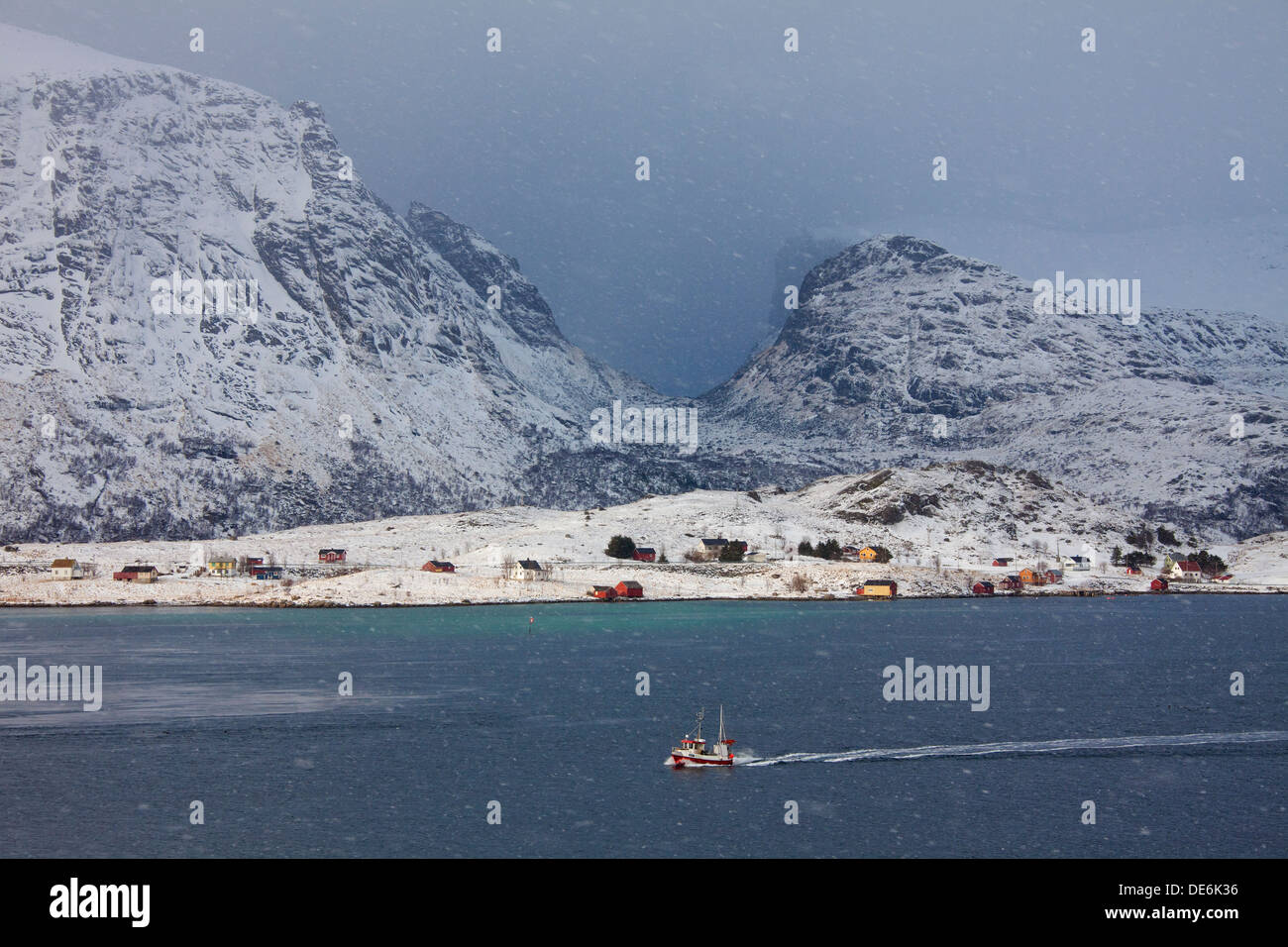 Fishing boat sailing through snowstorm in winter, Sundstraumen, Flakstad, Lofoten Islands, Norway Stock Photo