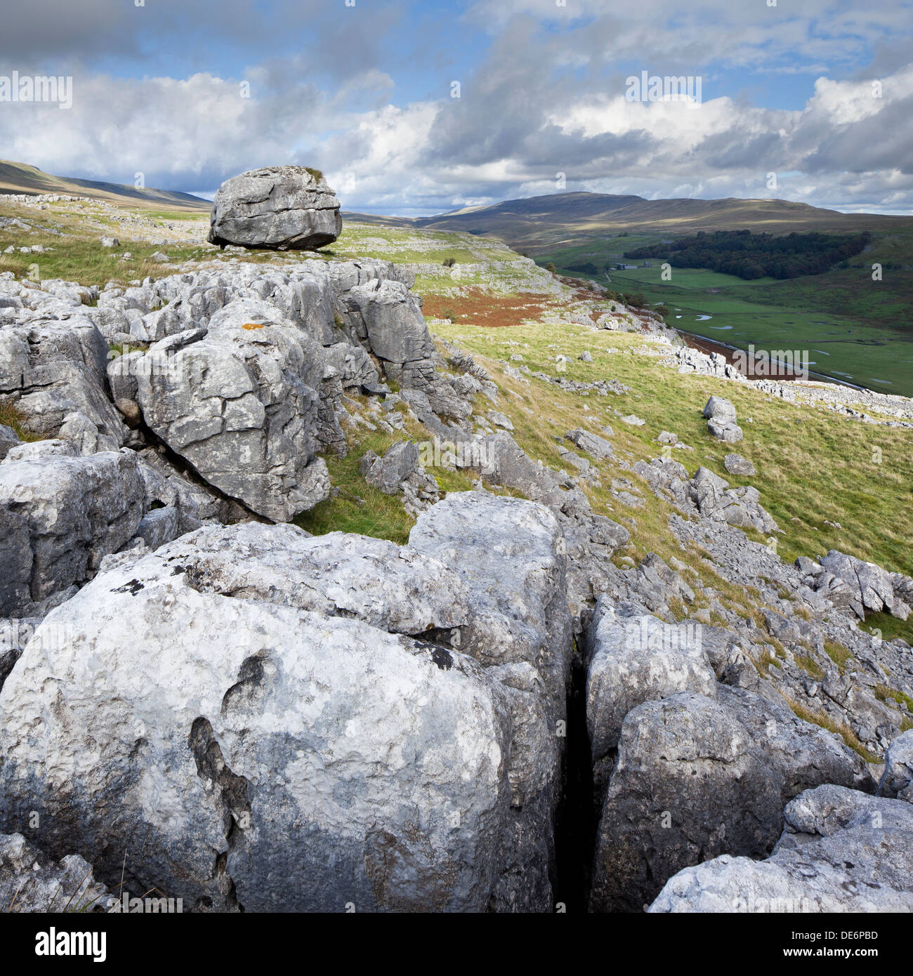 Large Glacial Erratic on Limestone pavement with Whernside visible in the distance, Keld Head Scar, Kingsdale, Yorkshire Dales Stock Photo